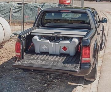 En mobil dieseltank på flaket på en svart pickup.