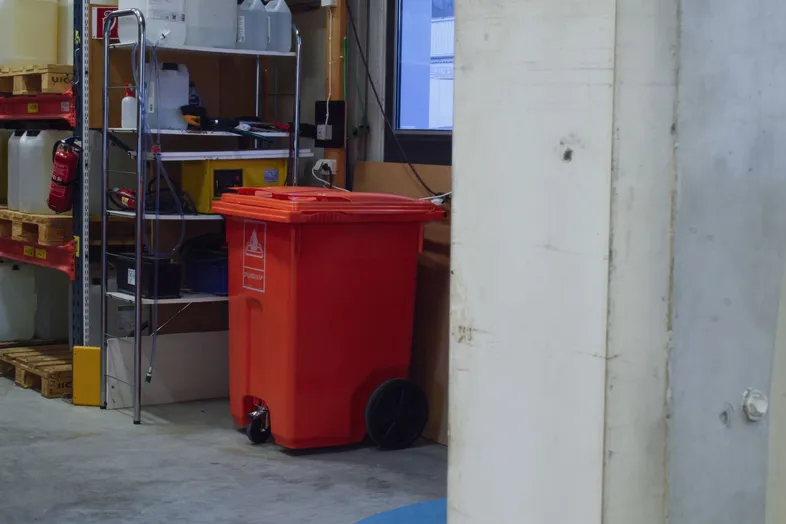 Ett orange kärl med texten spillredskap på ett lager.
